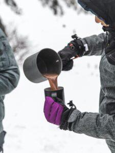 person in black winter  jacket pouring hot chocolate